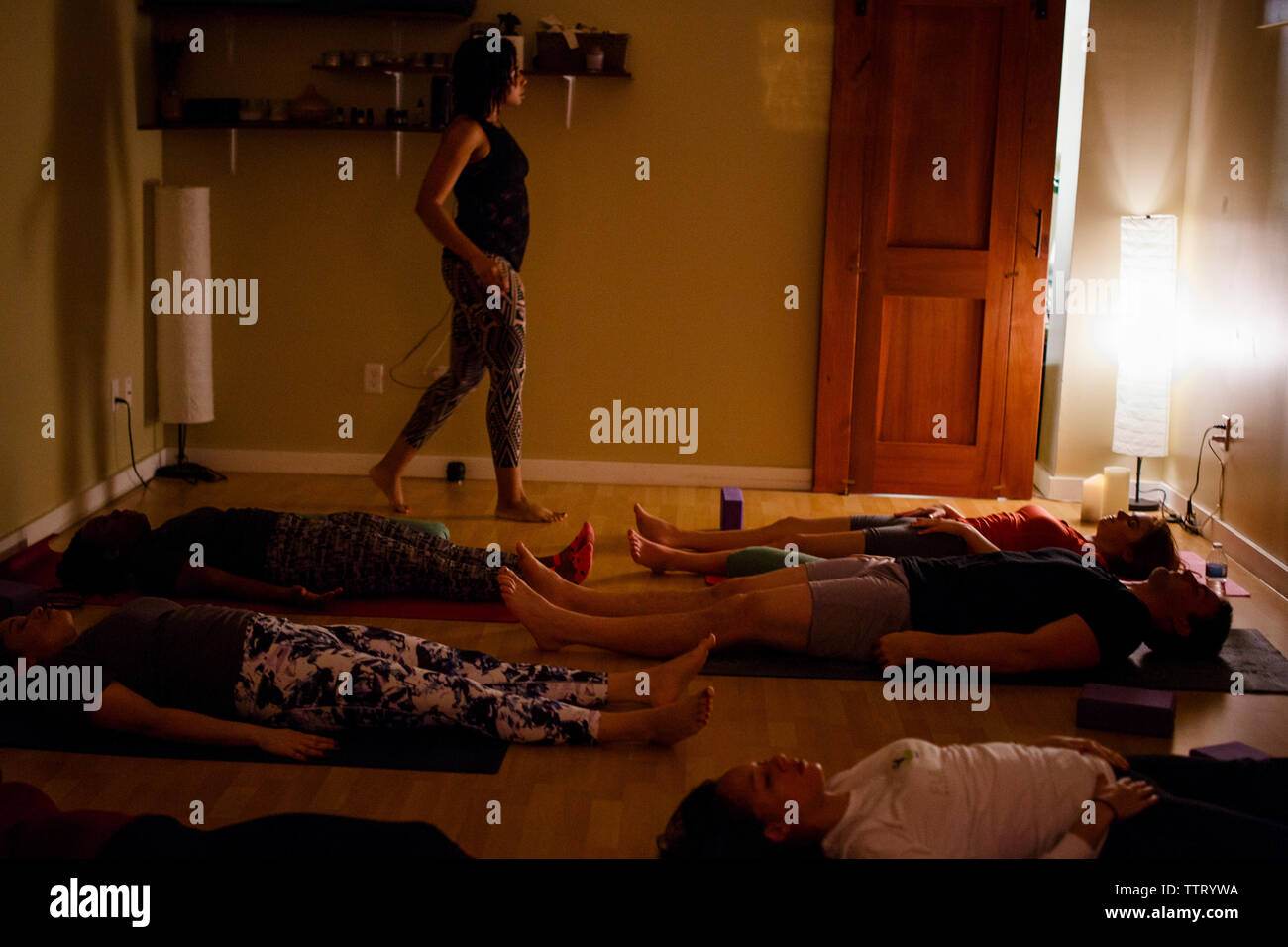 Eine weibliche yoga Kursleiter führt die Teilnehmer durch Meditation Übung Stockfoto