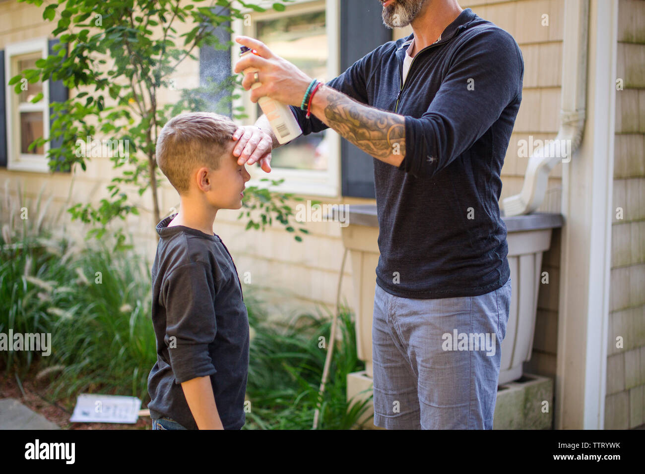 Ein Vater Sonnencreme auftragen, um seinen Sohn in den Hinterhof Stockfoto