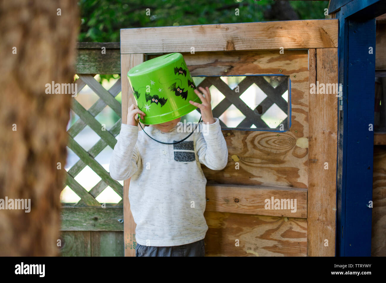 Ein kleiner Junge steht in einem Baumhaus mit einer Schaufel auf den Kopf. Stockfoto