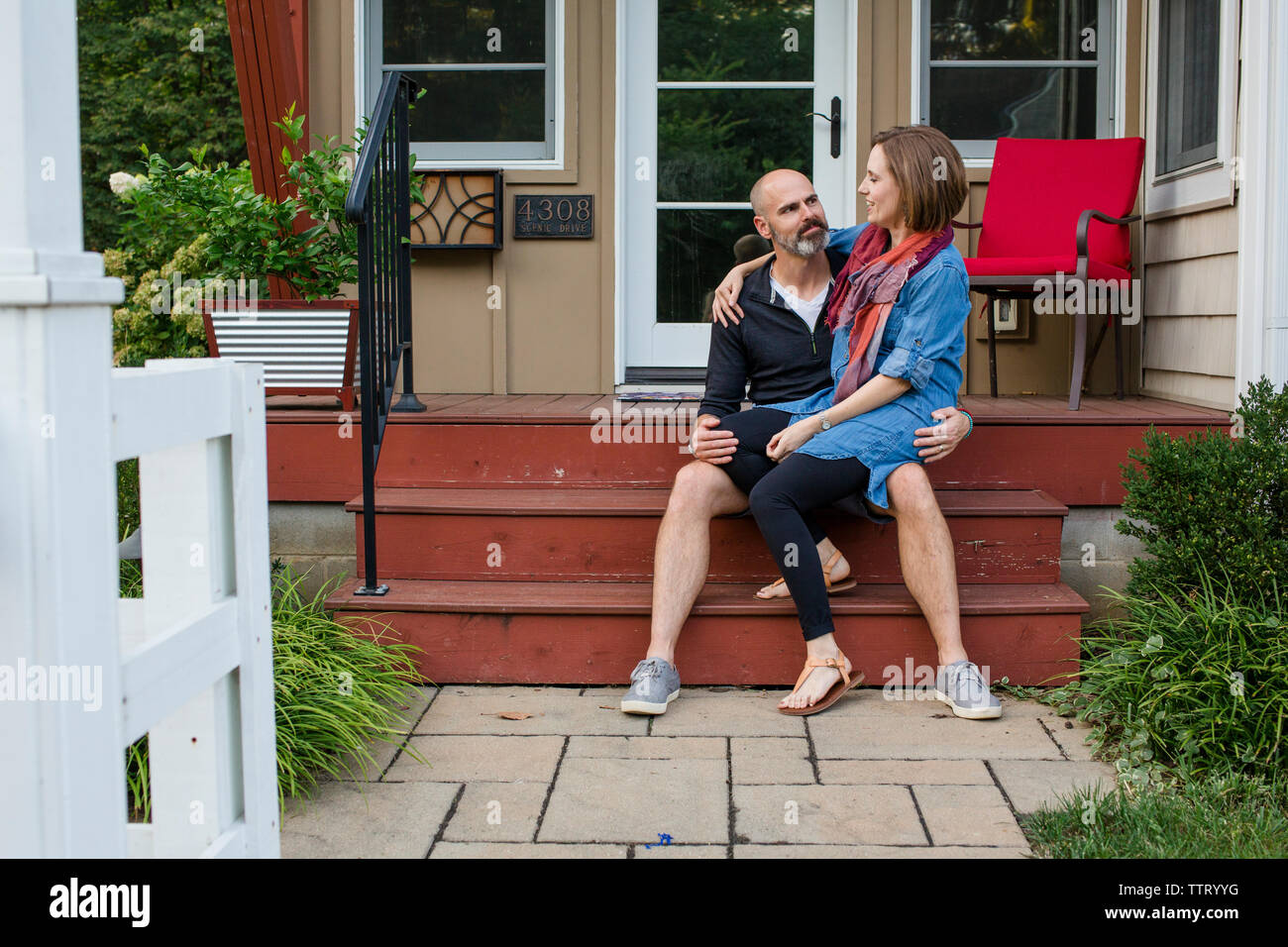 Eine Frau sitzt auf dem Schoß ihres Mannes vor Ihren home Stockfoto