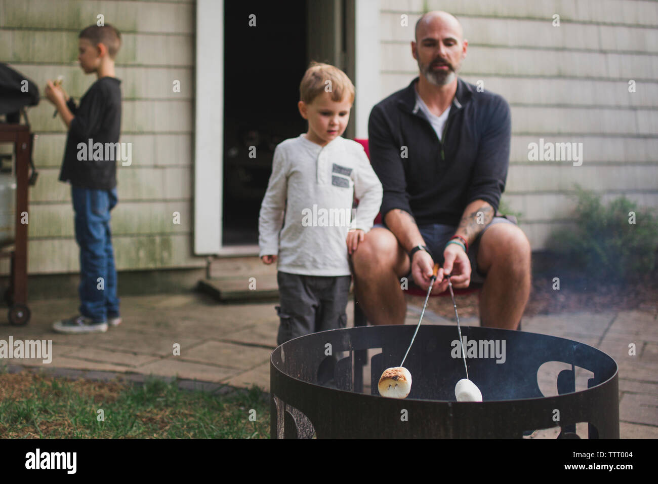 Ein Vater braten Marshmallows mit seinen Kindern über Feuerstelle Stockfoto