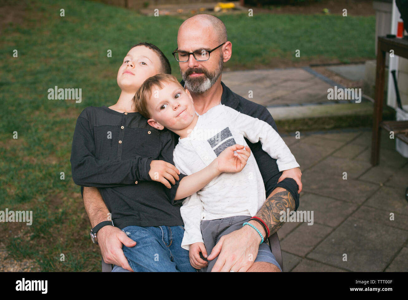 Ein glücklicher Vater hält seine beiden kleinen Kinder in seinen Schoß. Stockfoto
