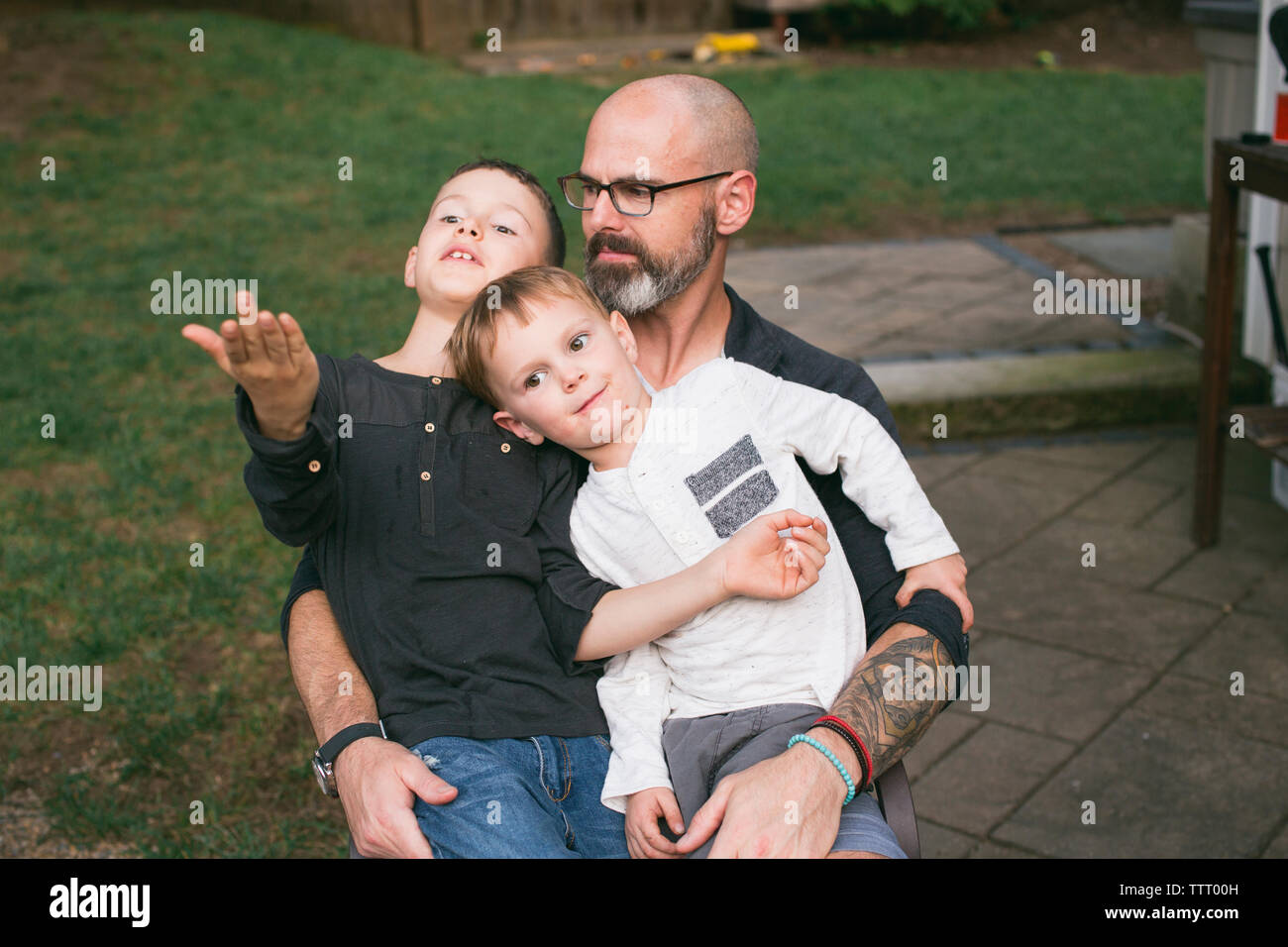 Ein glücklicher Vater hält seine beiden kleinen Kinder in seinen Schoß. Stockfoto