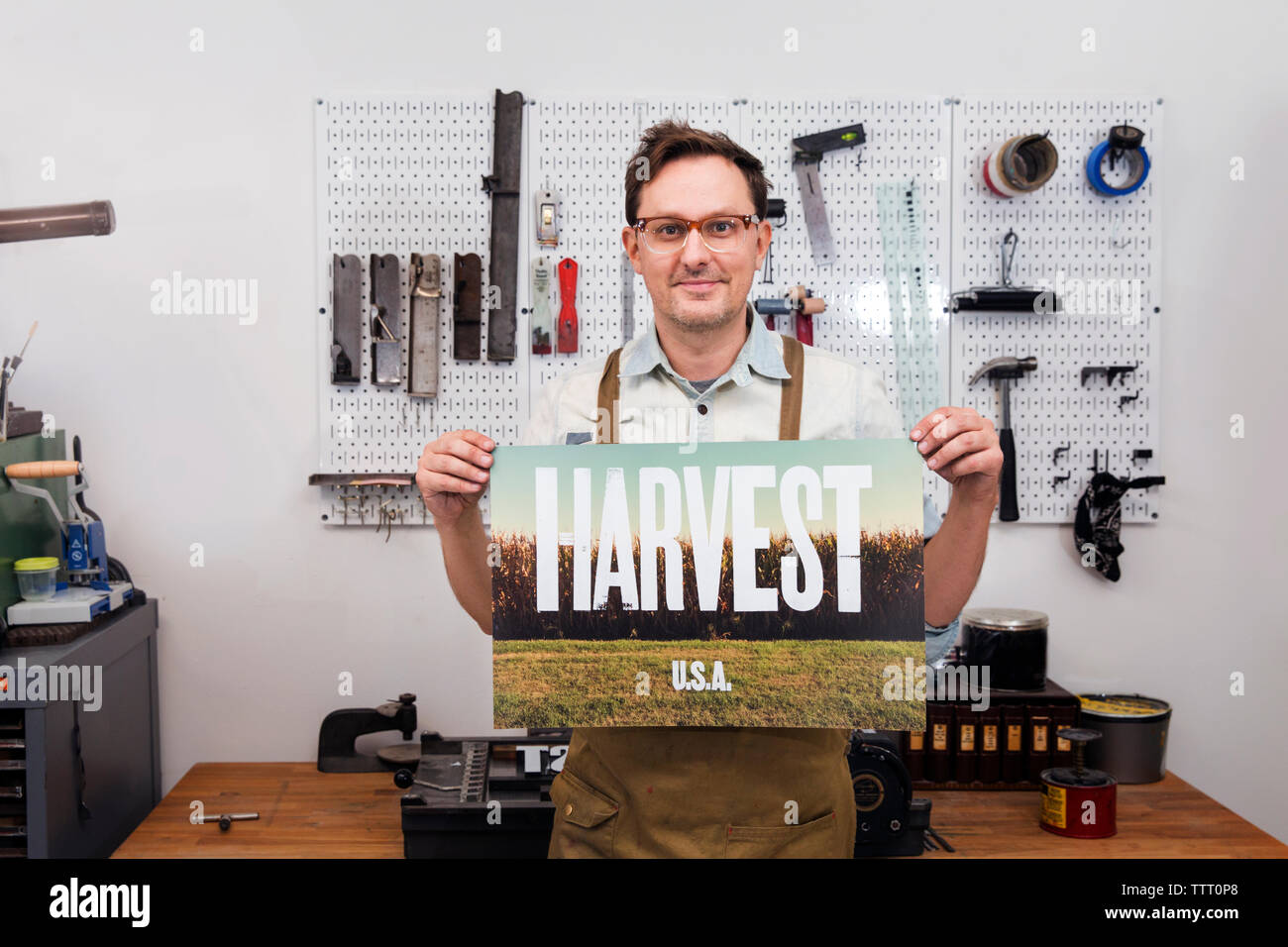 Männliche craftsperson Holding Poster und stehen in der Werkstatt Stockfoto