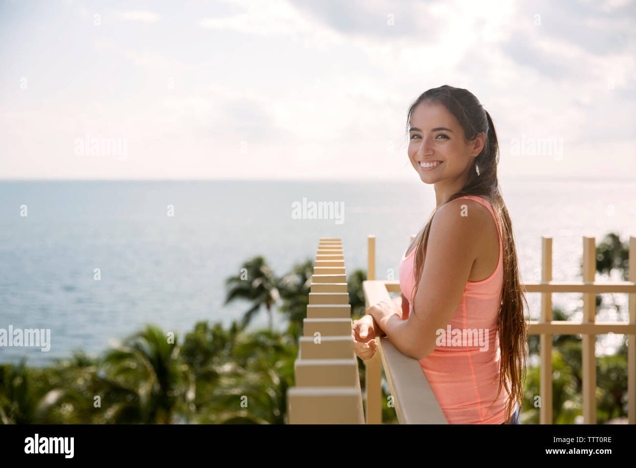 Portrait von glücklichen Frau, die an der Reling vor der See an einem sonnigen Tag Stockfoto