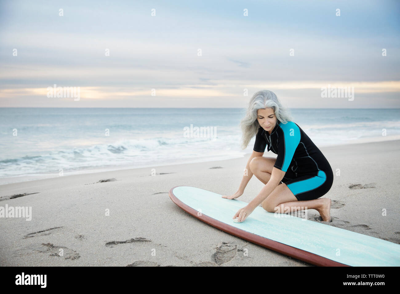 Weibliche surfer Reinigung Surfbrett am Delray Strand bei Sonnenuntergang Stockfoto