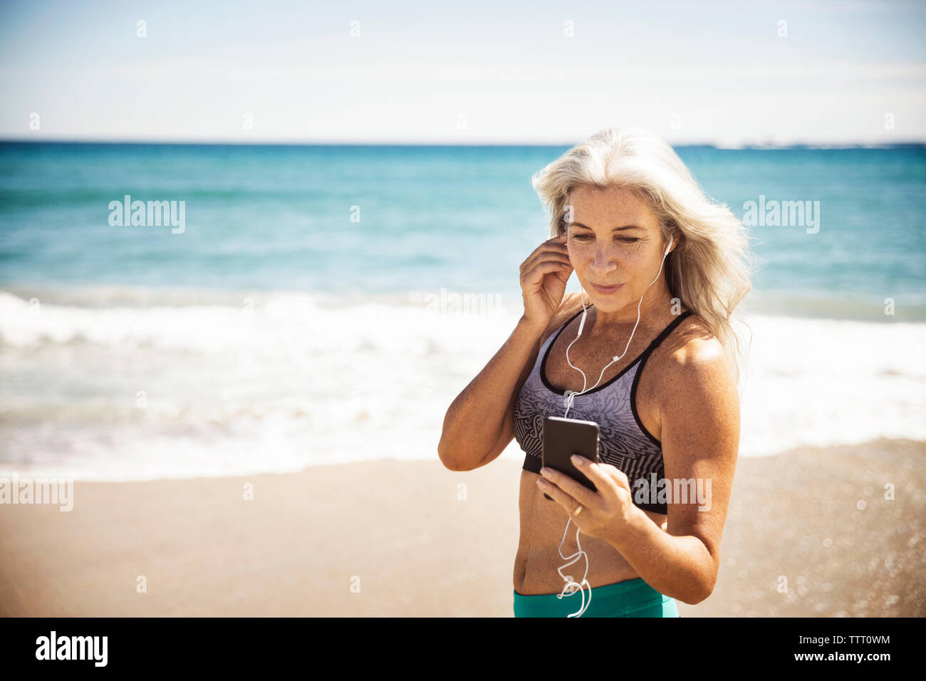 Montieren reifen Frau Musik hören durch Smart Phone in Delray Beach Stockfoto