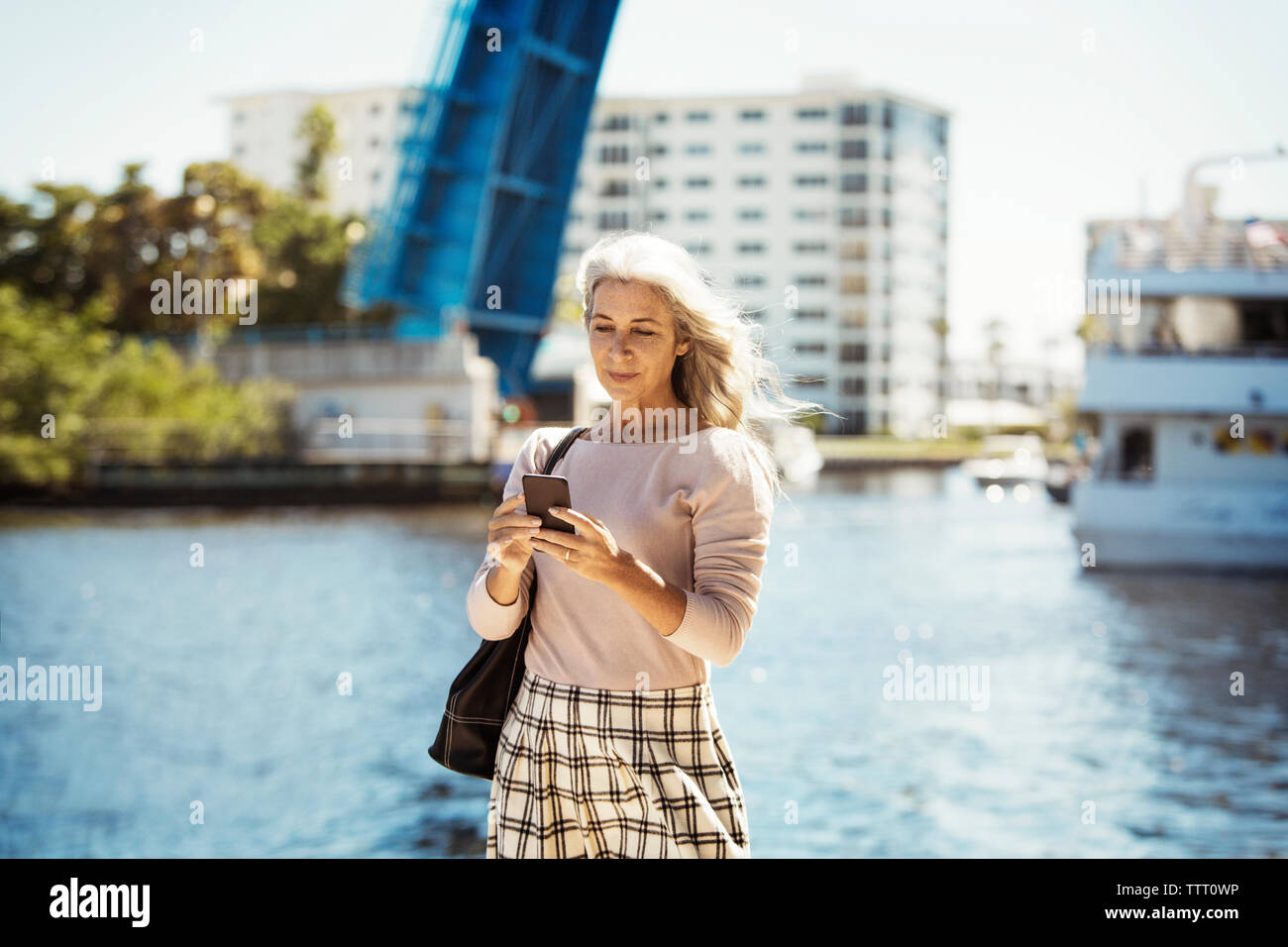 Reife Frau mit Handy durch den Fluss in der Stadt Stockfoto