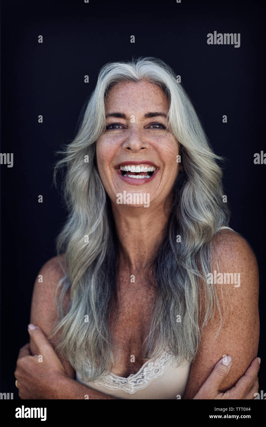 Portrait von fröhlichen reife Frau mit langen grauen Haaren vor blauem Hintergrund Stockfoto