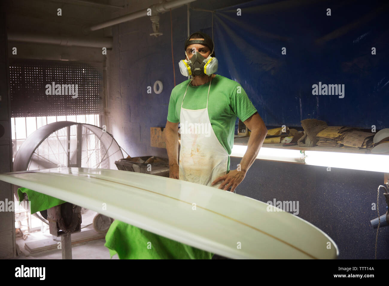 Porträt der Arbeiter in Schutzkleidung Arbeitskleidung stehen Surfbrett in Werkstatt Stockfoto