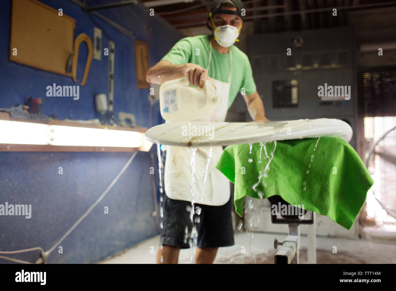 Arbeiter gießen Flüssigkeit zum Waschen des Surfbretts in der Werkstatt Stockfoto