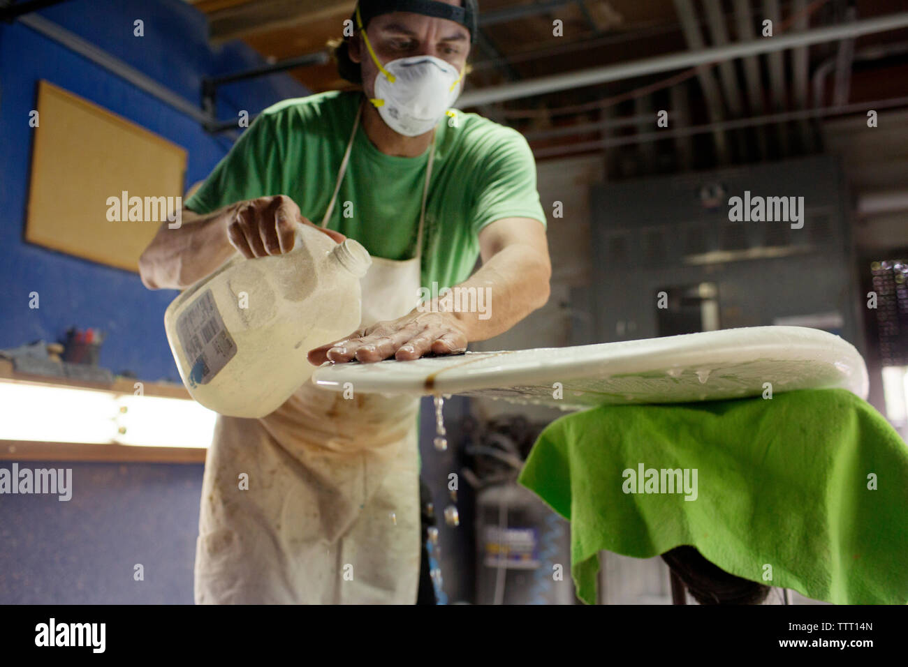 Arbeiter waschen das Surfbrett in der Werkstatt mit Flüssigkeit Stockfoto
