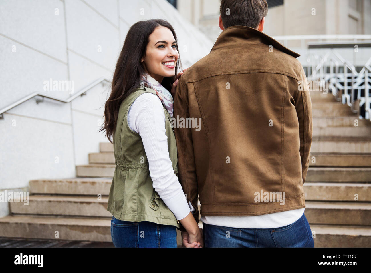 Glückliche Frau weg schauen, während die Schritte mit Freund Stockfoto