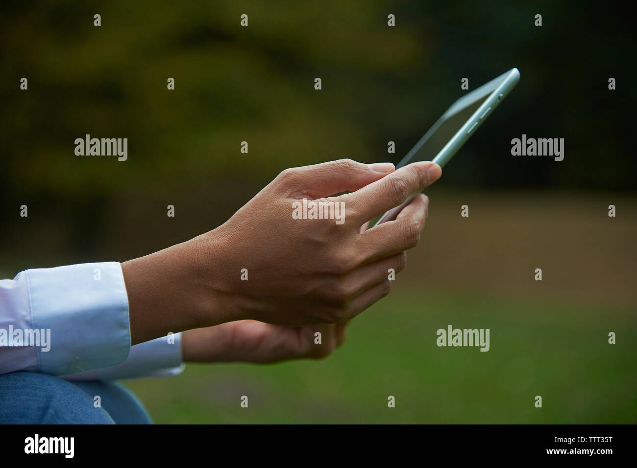 7/8 Hände der Geschäftsfrau holding Tablet Computer im Park Stockfoto