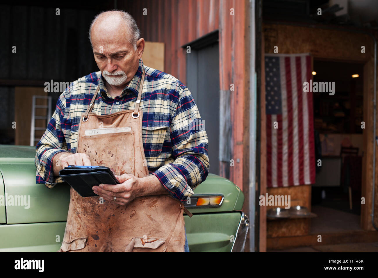 Senior Handwerker mit digitalen Tablet beim Stehen außerhalb der Werkstatt Stockfoto