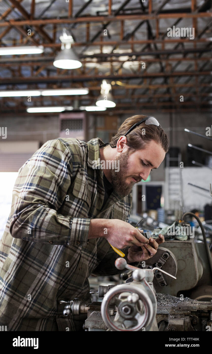 Ernsthafte Mechaniker auf Maschinen in der Werkstatt arbeiten Stockfoto