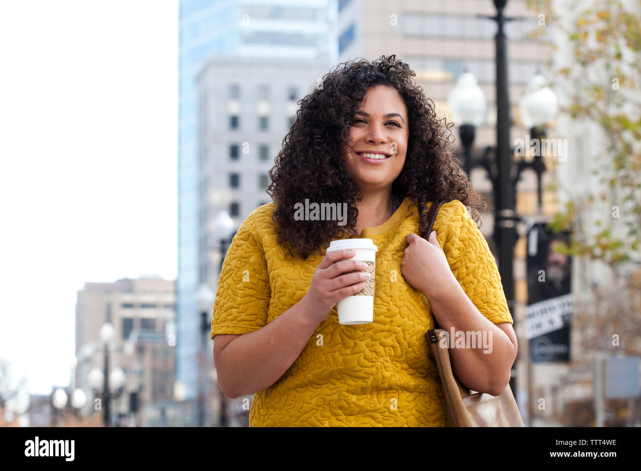 Lächelnde Frau mit Einweg Becher und Bürgersteig stehend Stockfoto