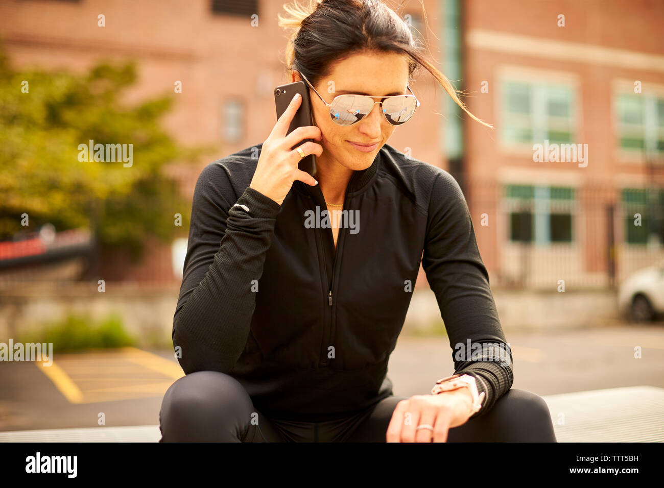 Eine Frau schaut sie Fitness beobachten, während Sie auf Ihrem Smartphone. Stockfoto