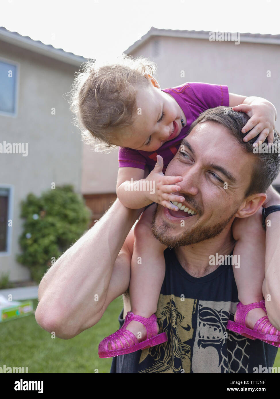 Nahaufnahme der glückliche Vater mit Tochter auf den Schultern beim Stehen im Hof Stockfoto