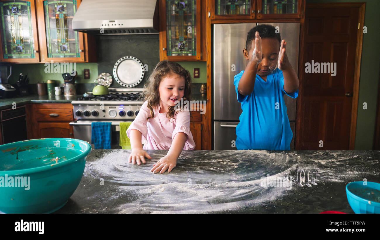 Jungen und Mädchen spielen mit Mehl in der Küche Stockfoto
