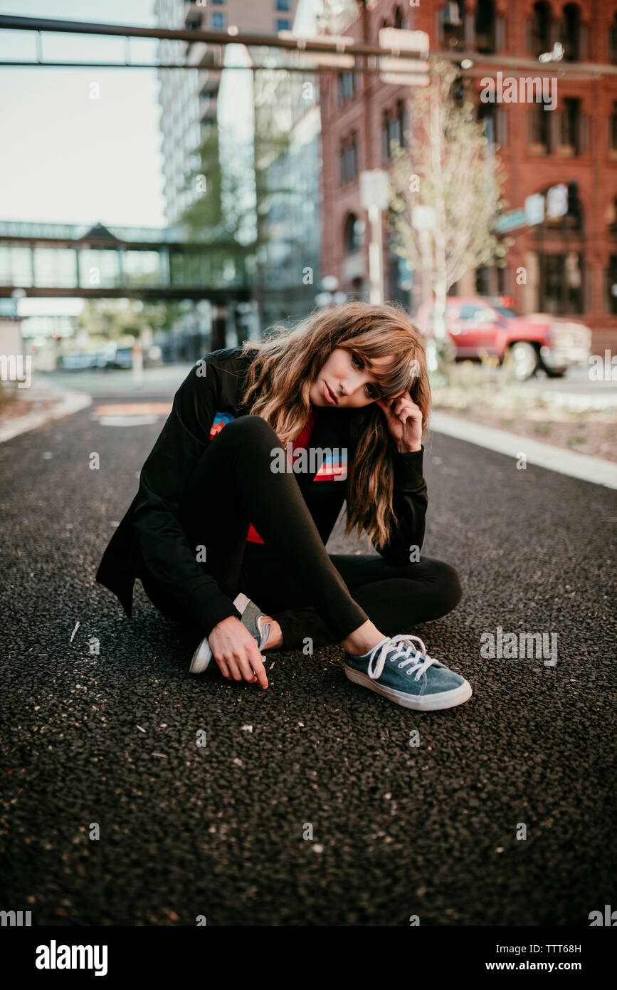 Portrait von selbstbewusste Frau mit Kopf schief sitzen auf der Straße in der Stadt Stockfoto