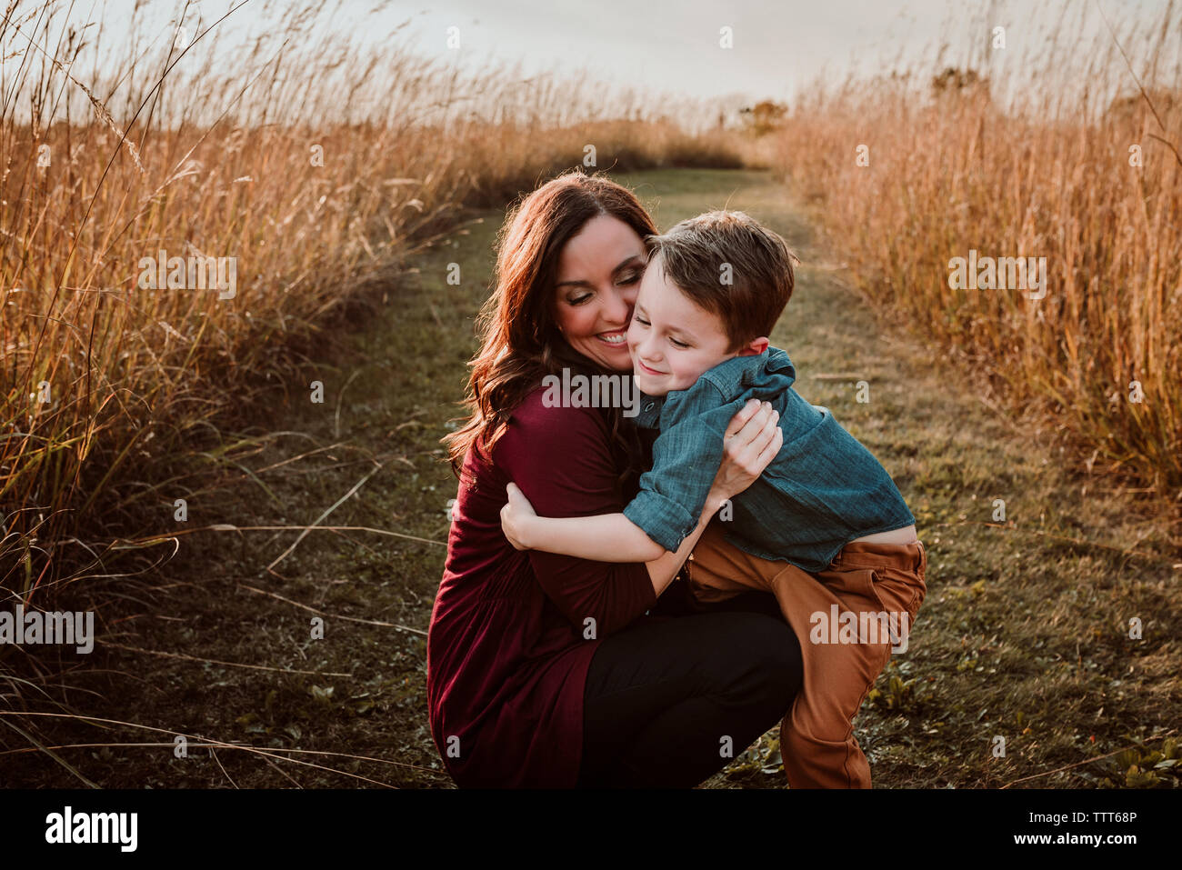 Fröhliche Mutter mit Sohn crouching inmitten von Feld Stockfoto