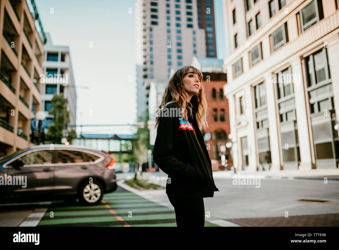 Seitenansicht der jungen Frau mit Händen in den Taschen auf der Stadt. Stockfoto