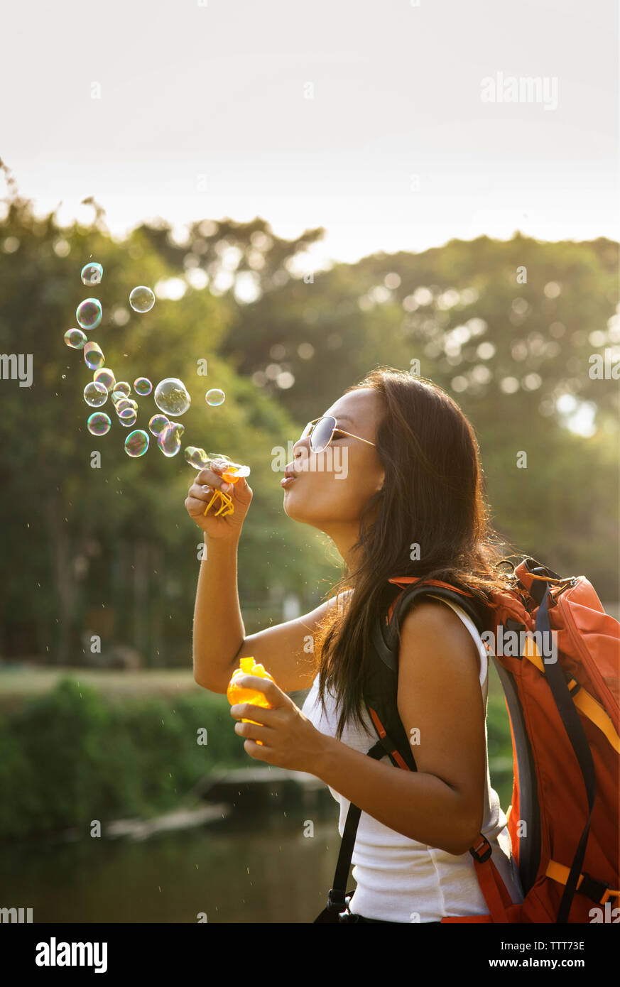 Verspielte Frau blowing bubbles gegen den Himmel an einem sonnigen Tag Stockfoto