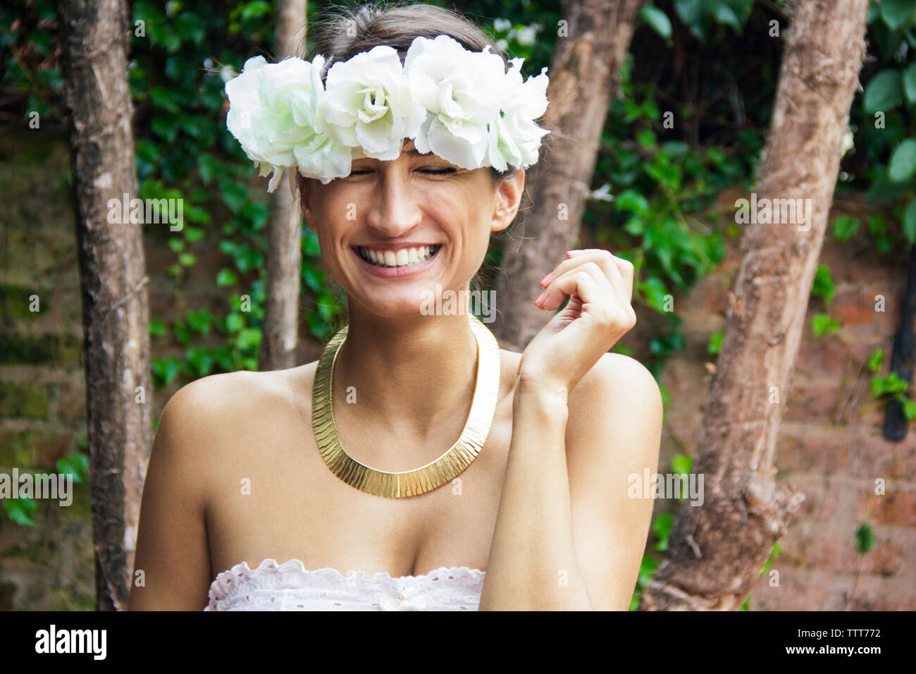 Lächelnde junge Frau mit Blume Kopfbügel Stockfoto