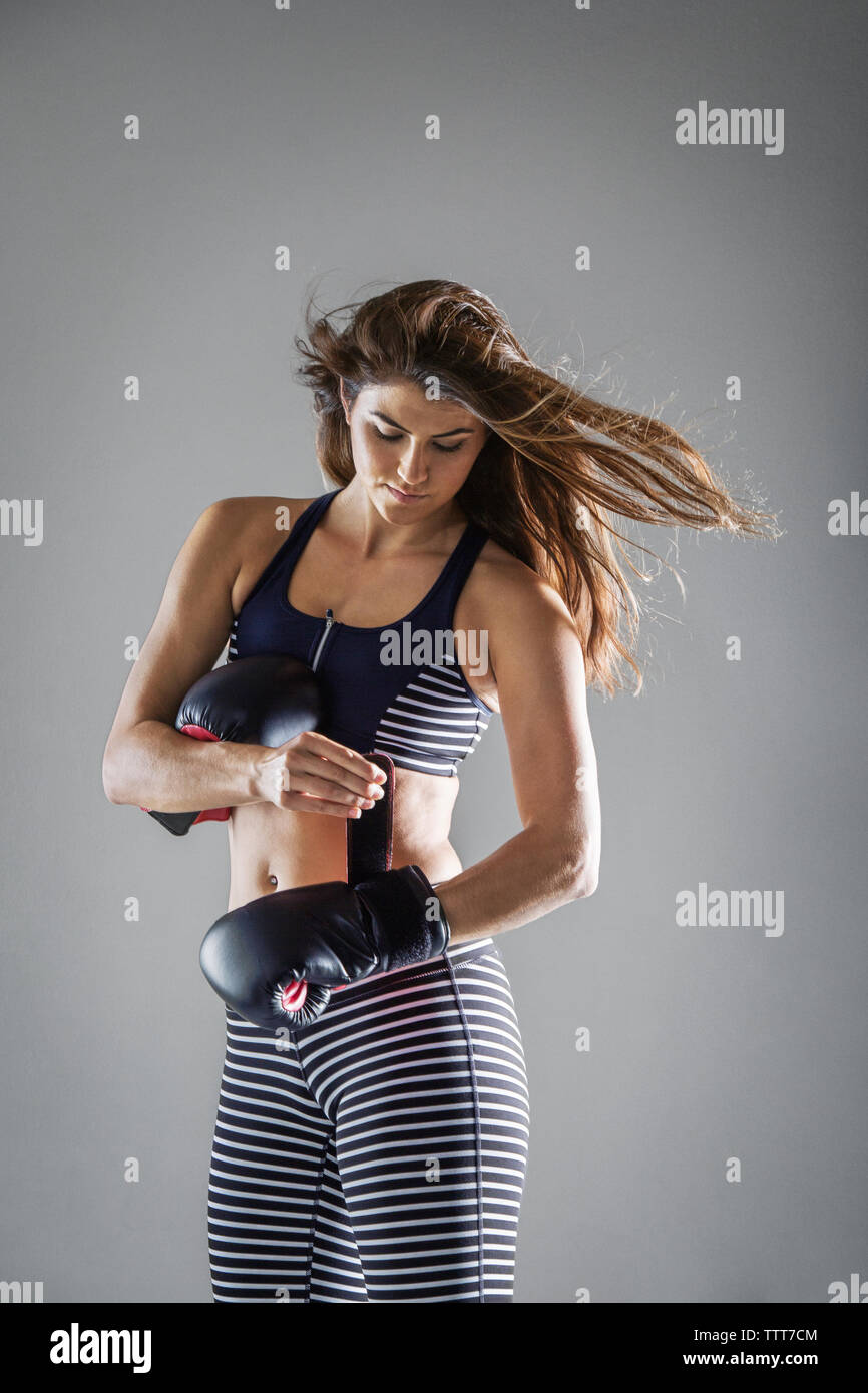 Frau Boxhandschuh während gegen grauen Hintergrund stehend Stockfoto