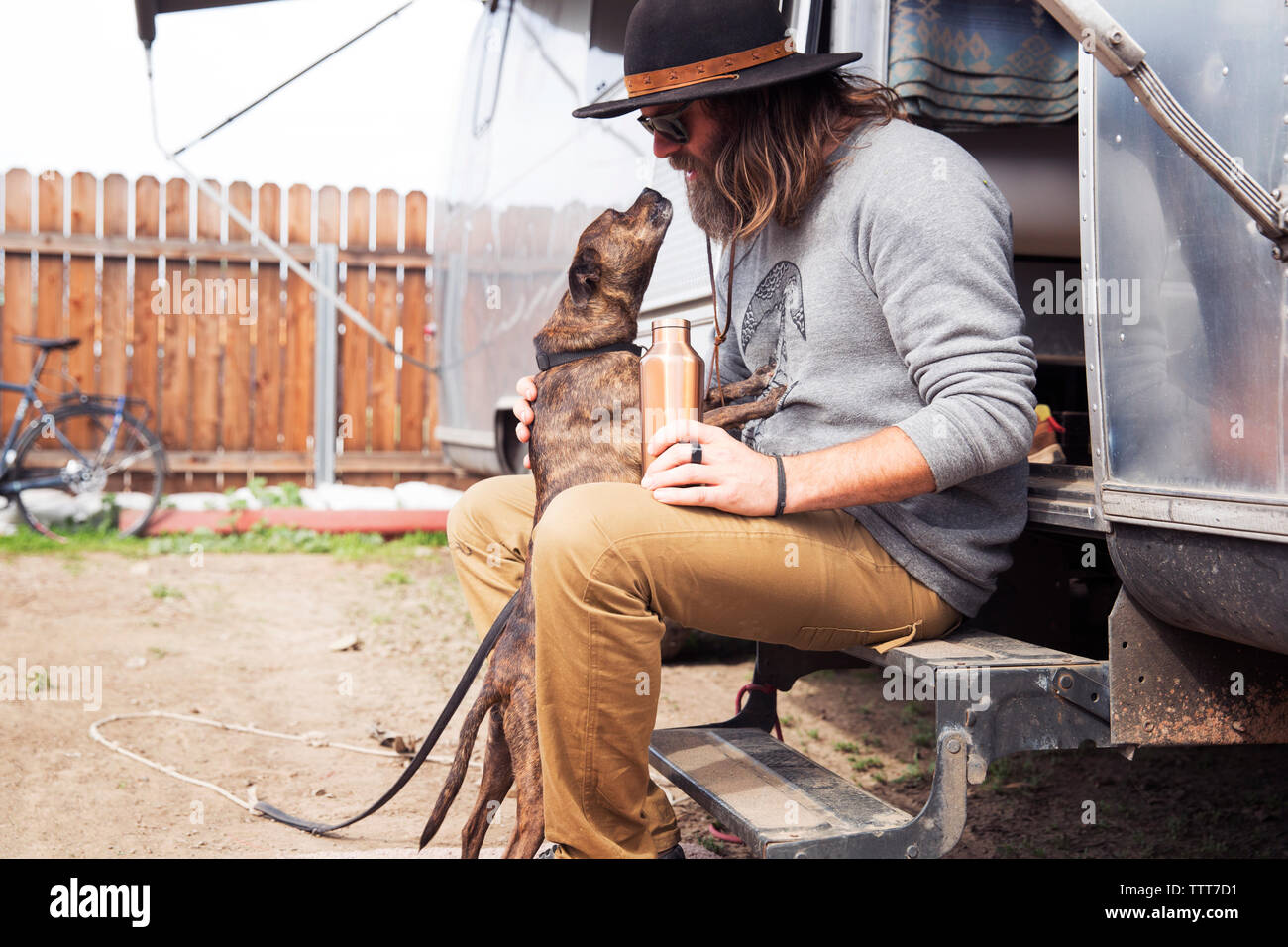Mann mit Hund sitzend auf Schritte von Camper van Stockfoto