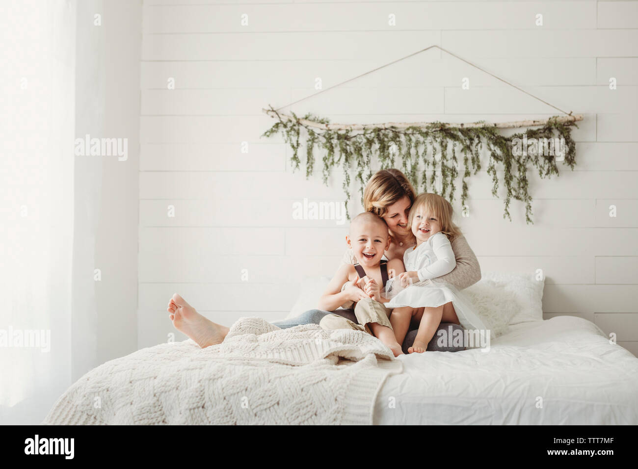 Glückliche Mutter mit Kindern sitzen auf dem Bett zu Hause. Stockfoto