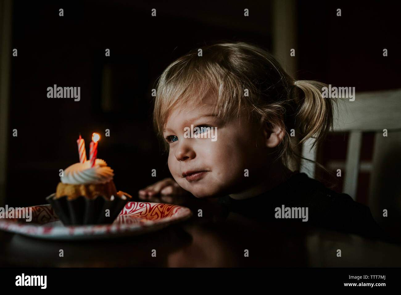 Nettes Mädchen an ihrem Geburtstag Kuchen auf dem Tisch Stockfoto