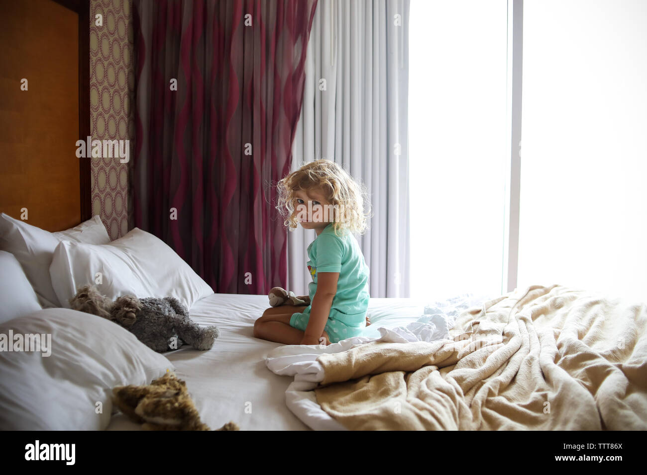 Kleines Mädchen auf dem Bett mit bedhead Schlafanzüge tragen Stockfoto