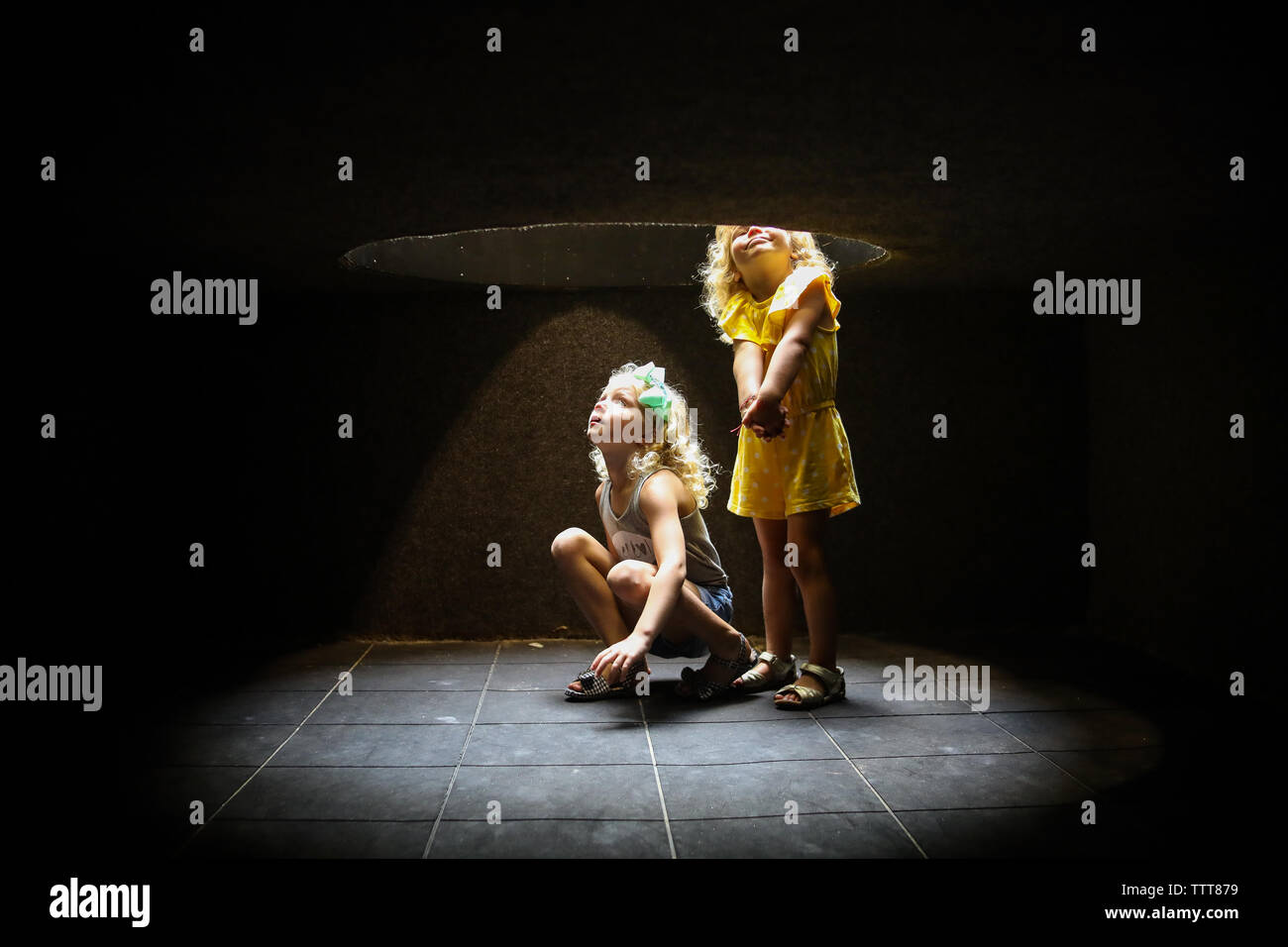 Zwei Mädchen hocken, um Licht durch Tunnel Stockfoto