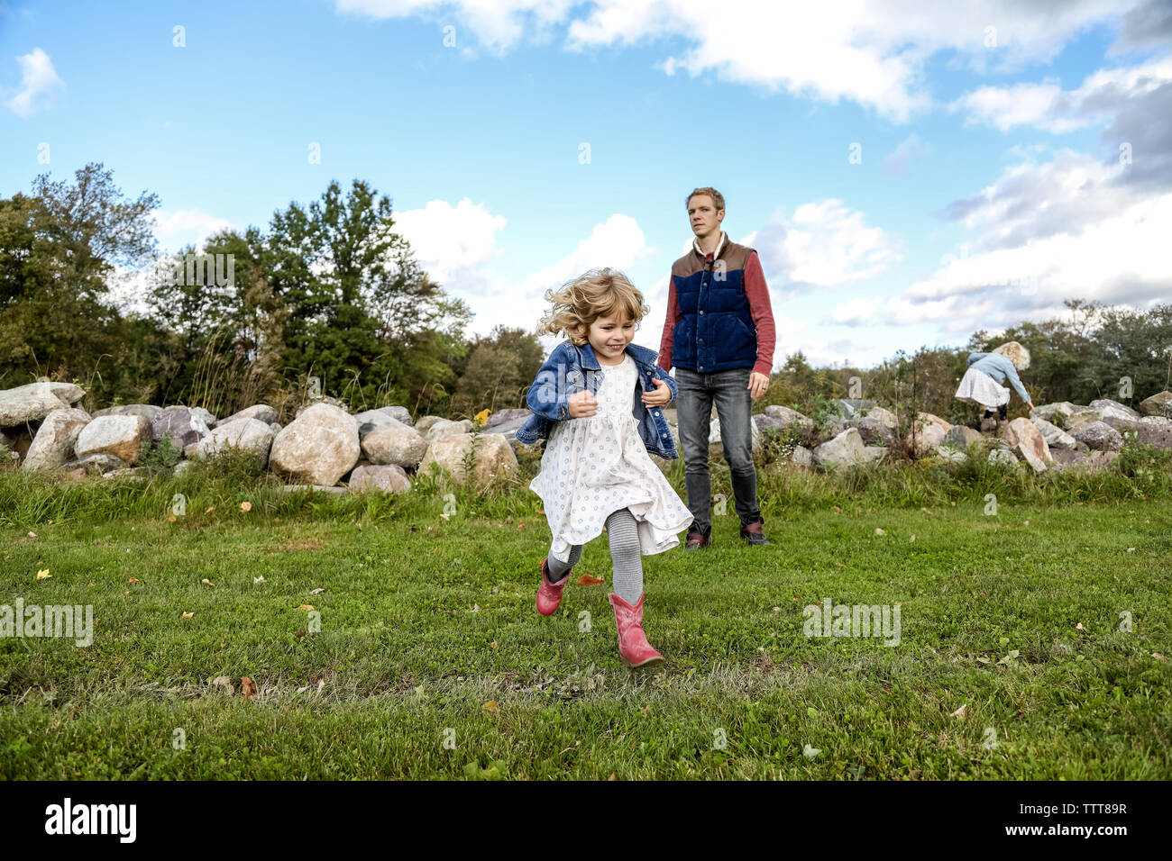 Kleine Mädchen in Richtung Kamera läuft weg von Vati im Feld Stockfoto