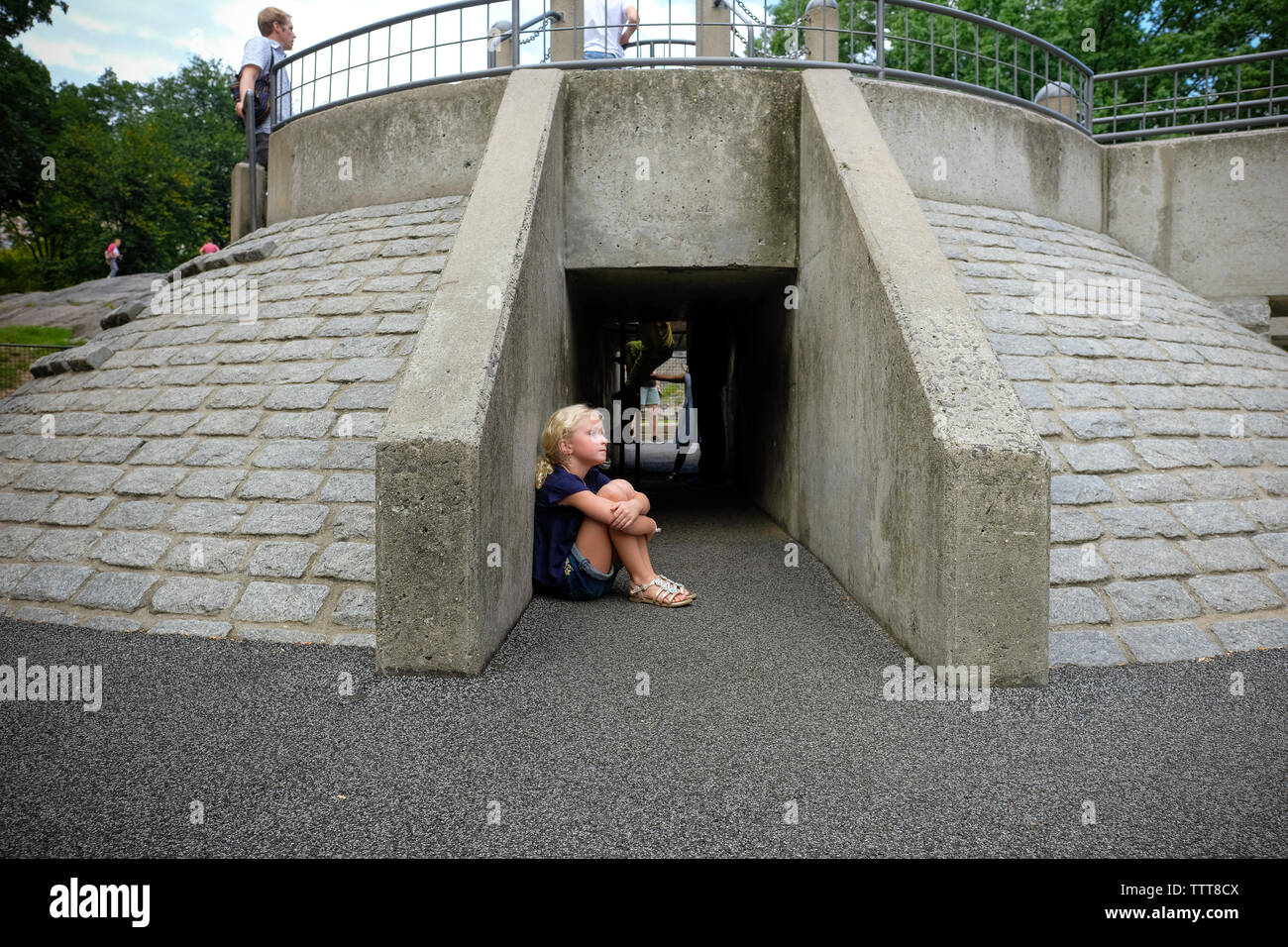 Junges Mädchen sitzen in Zement spielen Struktur in den städtischen Spielplatz Stockfoto