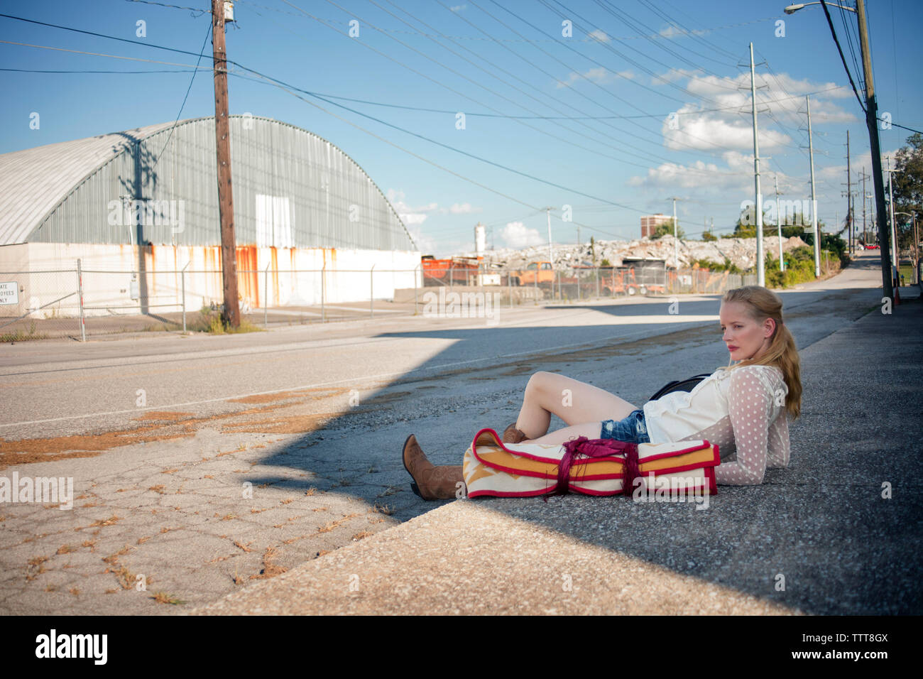 Nachdenklich liegende Frau auf dem Bürgersteig vor der Fabrik Stockfoto