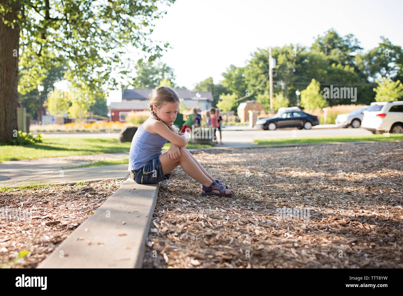 Seitenansicht des traurigen Mädchen sitzen auf Fußweg Stockfoto