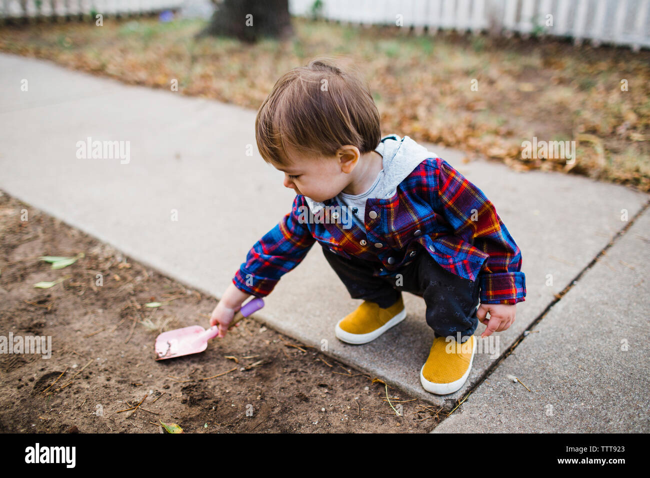 Baby Boy spielen mit Spielzeug Schaufel während kauert auf Rasen Stockfoto