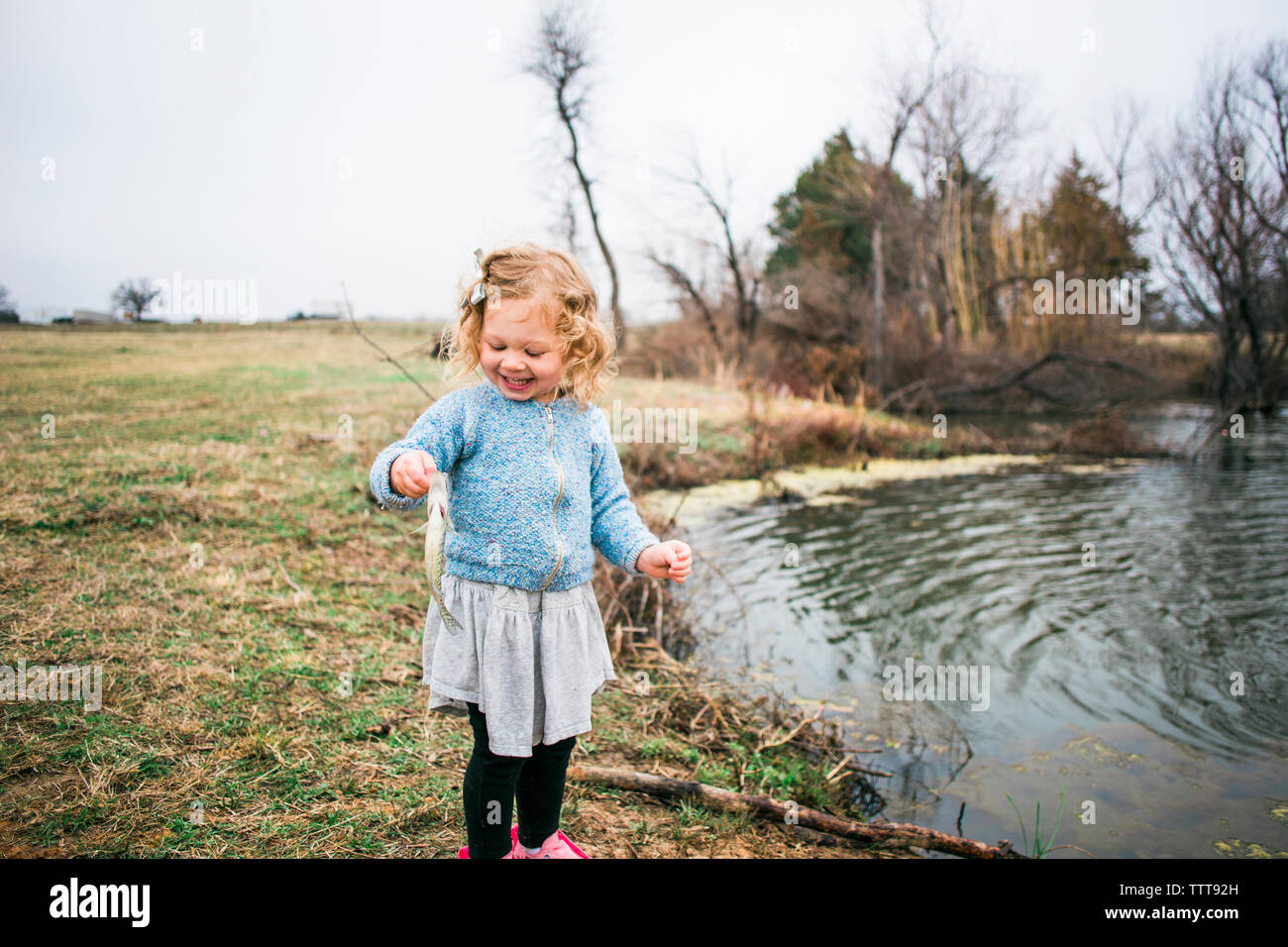 Fröhliches Mädchen holding Fisch beim Angeln am See Stockfoto