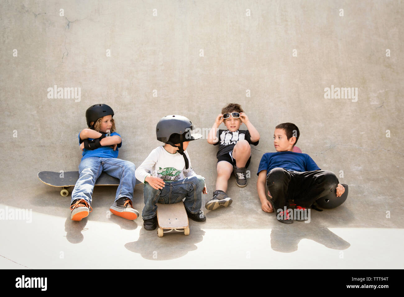 Jungen sprechen beim Sitzen auf Skateboard Rampe Stockfoto