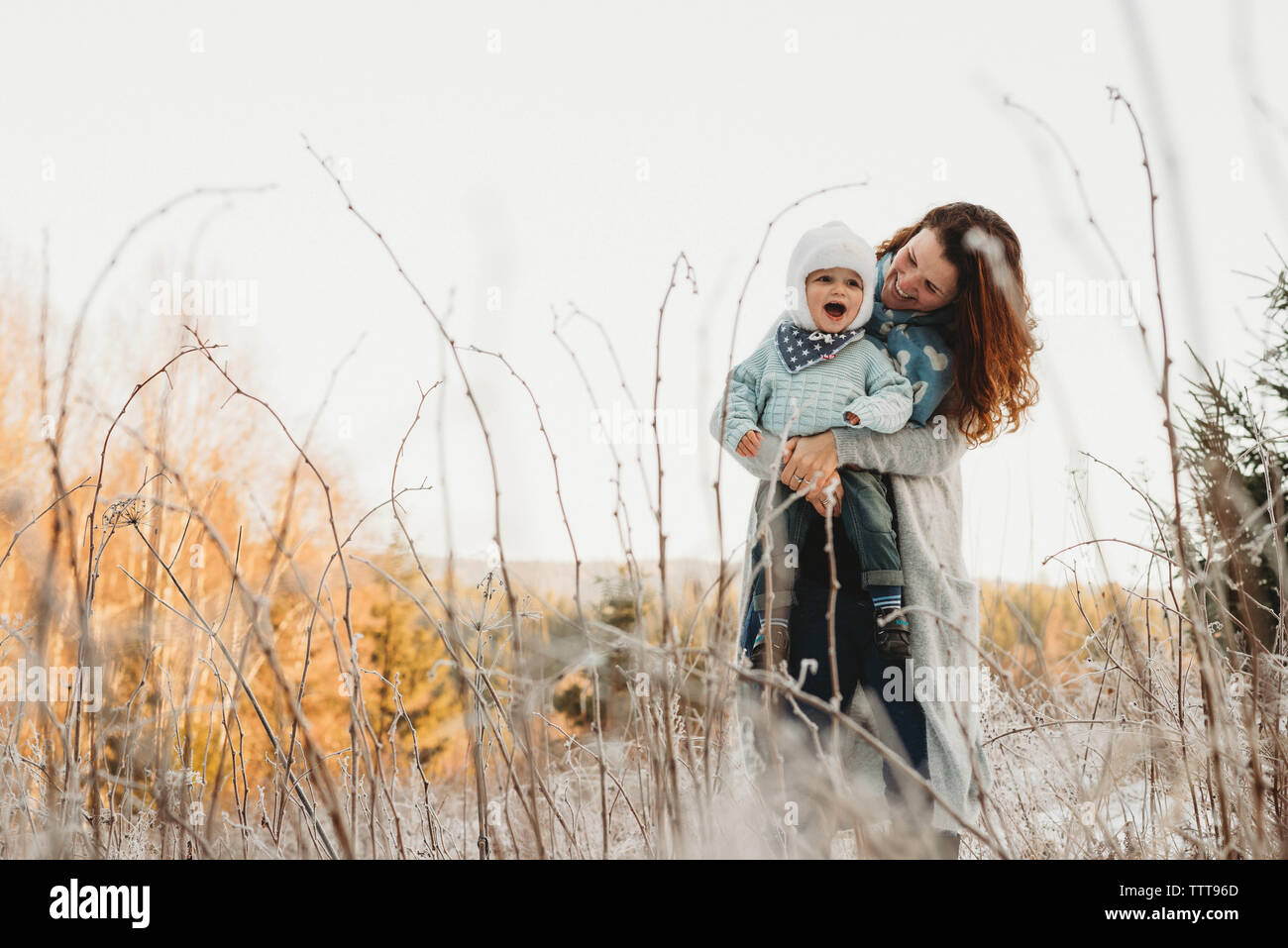 Mutter und Kind Junge lachend im Schnee Winter Wonderland Stockfoto