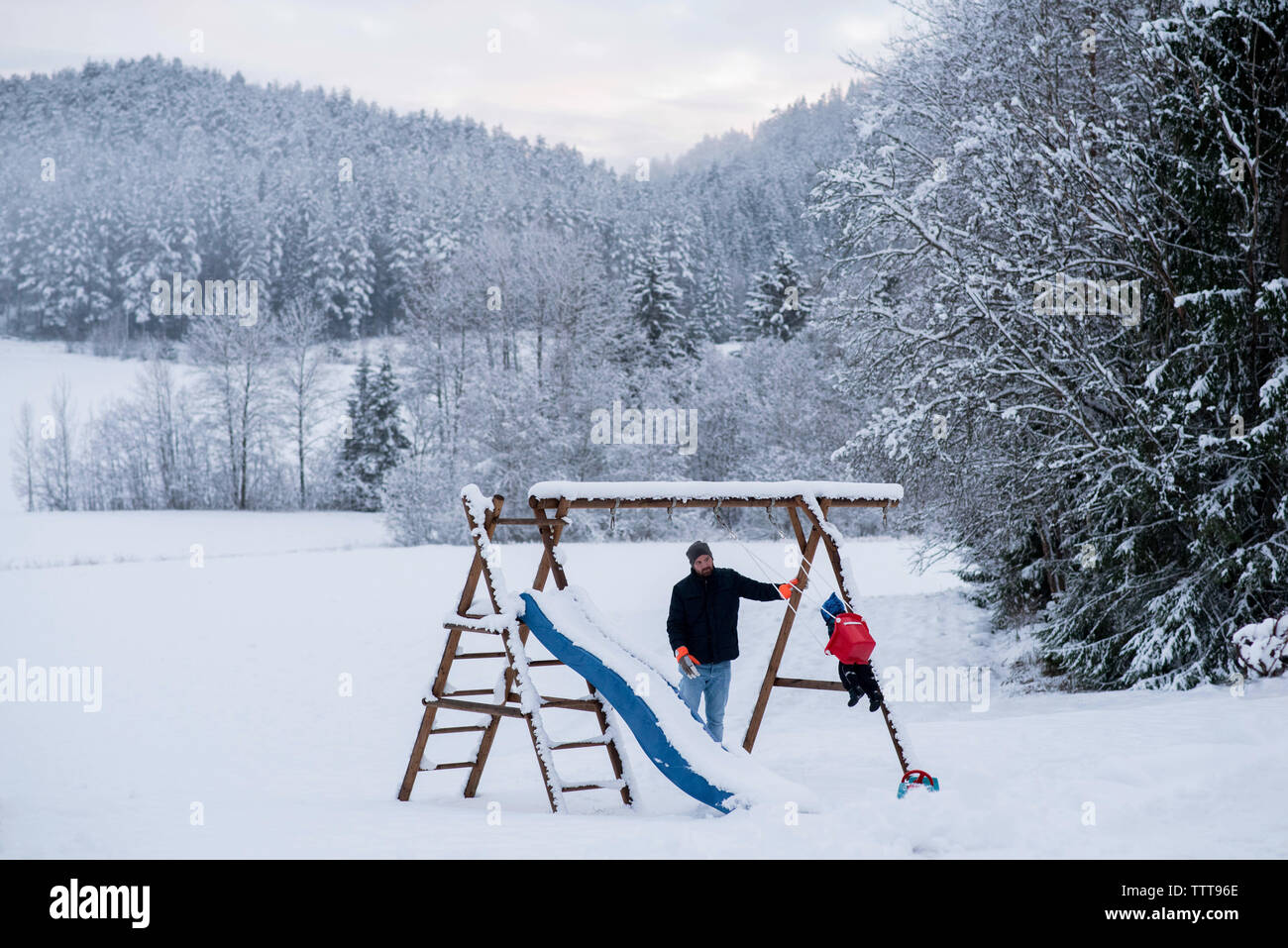 Vater Sohn spielen Hängematte in Snow White wald winter wonderland Stockfoto