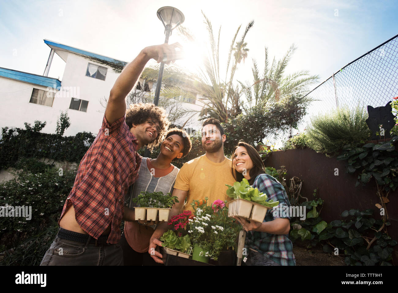 Glücklich, multi-ethnischen Freunde unter selfie Halten sie Topfpflanzen in Gemeinschaft garten Stockfoto