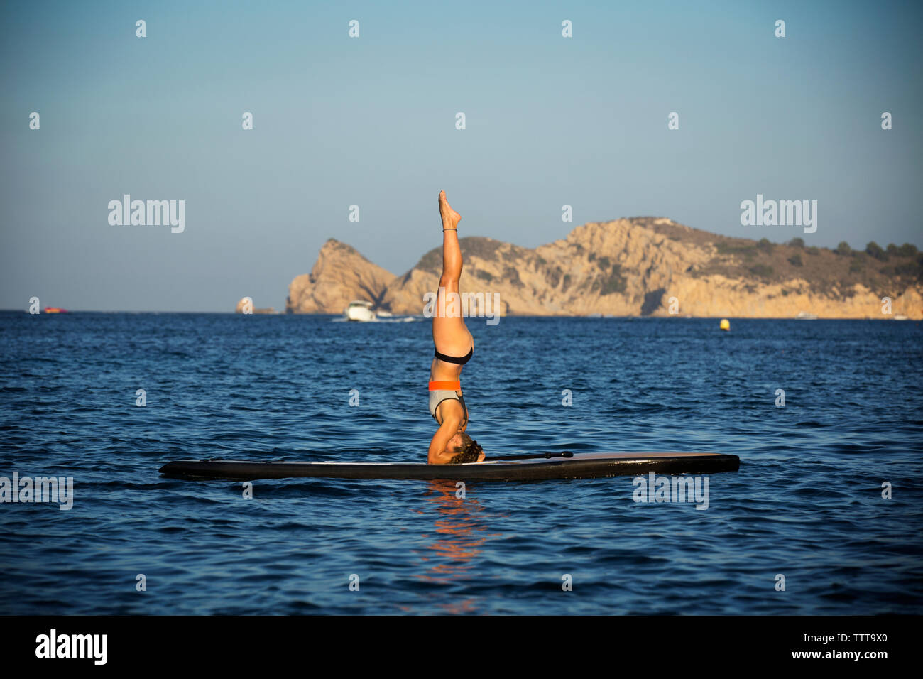 Weibliche Athleten trainieren auf paddleboard auf See gegen den klaren Himmel Stockfoto