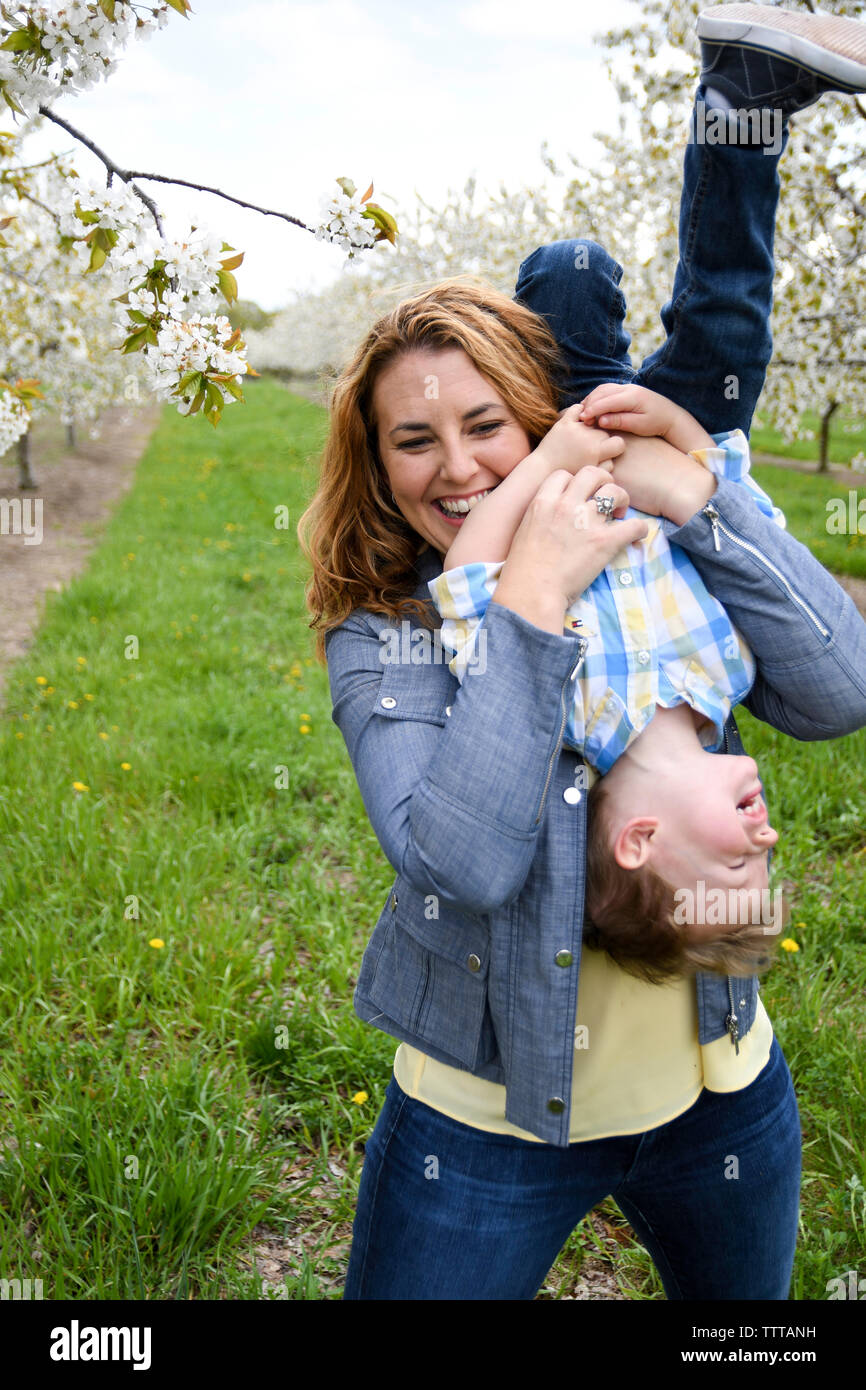 Glückliche Mutter spielt mit Sohn beim Stehen im Park Stockfoto