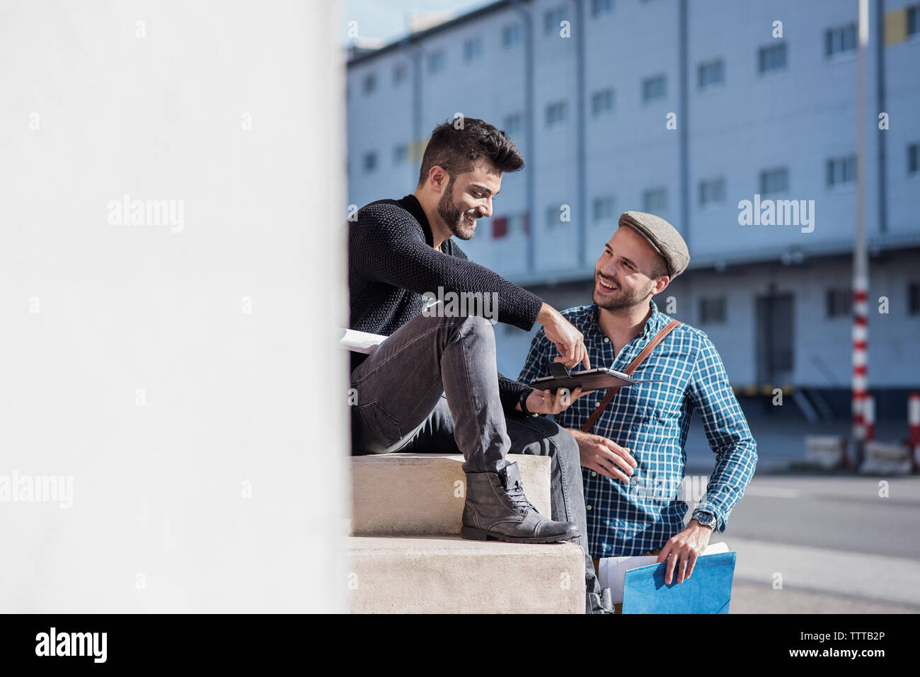 Freunde sprechen, während sie Tabletten gegen Gebäude in der Stadt Stockfoto