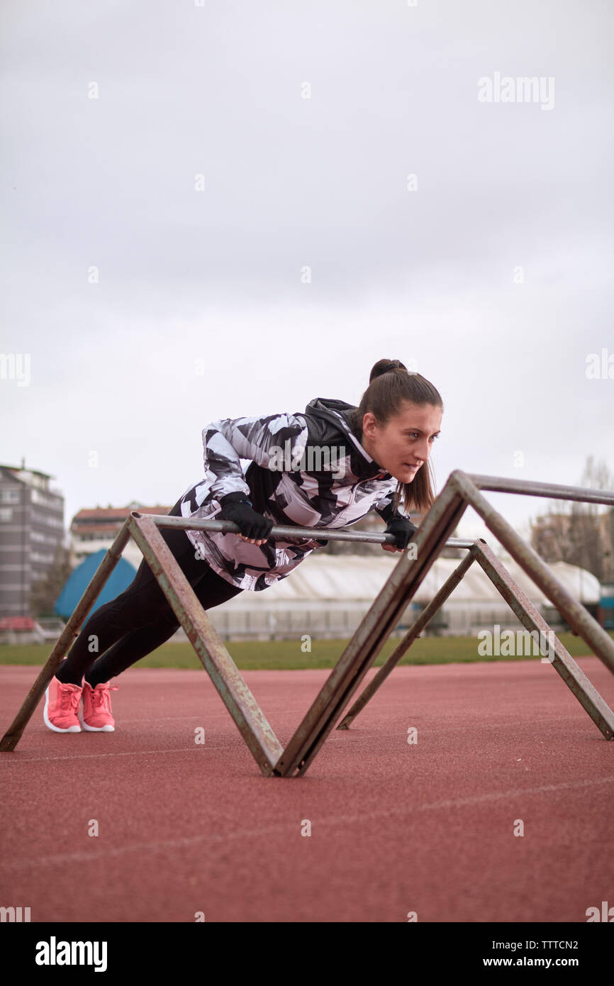 Weibliche Athleten trainieren auf Gymnastik Bars gegen Himmel am Sportplatz Stockfoto