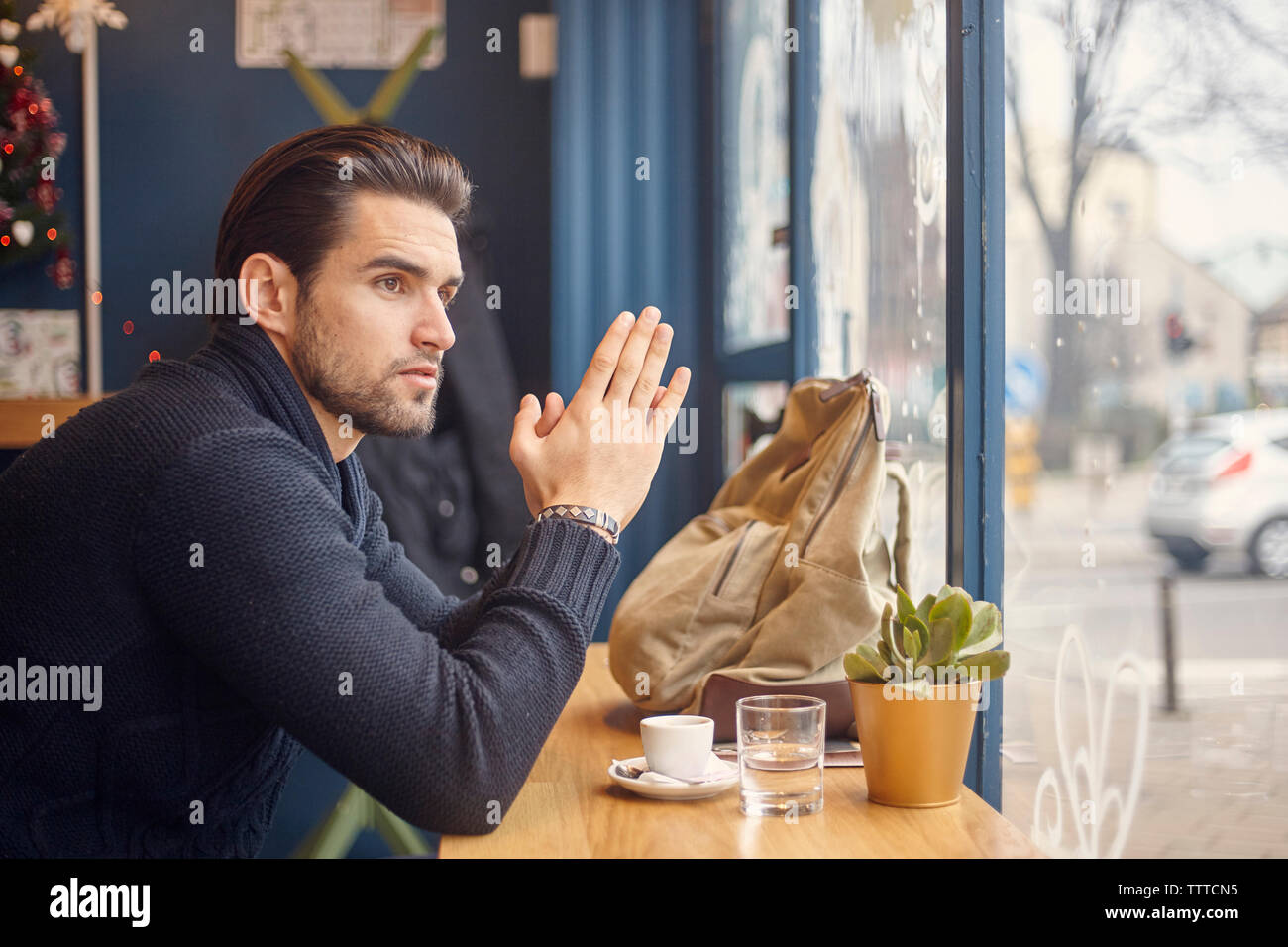 Seitenansicht des Menschen suchen, durch das Fenster beim Sitzen im Cafe Stockfoto
